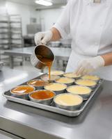 Confeiteira de touca e luvas colocando calda de caramelo em pudins